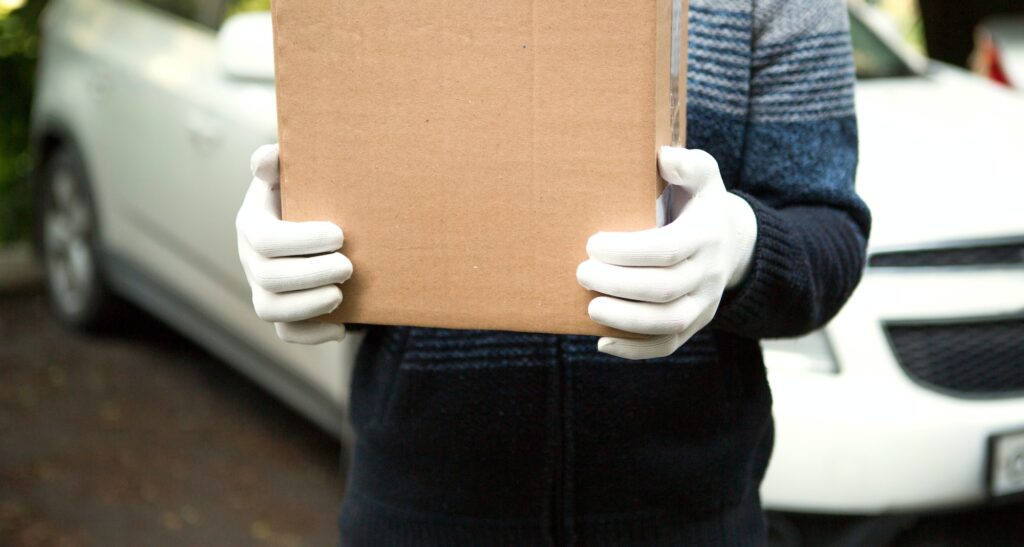 A cardboard box with space for text in the hands of a male courier in white gloves