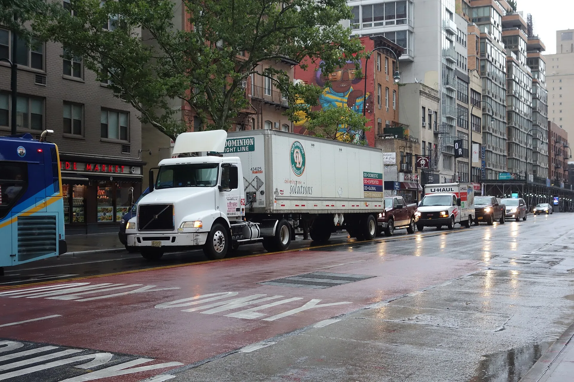 White tractor pulling an Old Dominion Freight Line LTL trailer on a wet city street