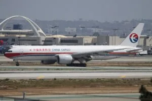 Boeing 777F բեռնատար ինքնաթիռը Լոս Անջելեսի միջազգային օդանավակայանի թռիչքուղու վրա, նրա հետևում՝ Theme Building-ը
