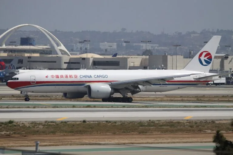 Boeing 777F բեռնատար ինքնաթիռը Լոս Անջելեսի միջազգային օդանավակայանի թռիչքուղու վրա, նրա հետևում՝ Theme Building-ը