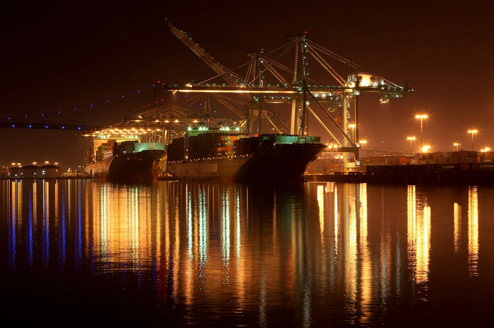 Evergreen container ships under gantry cranes at the Port of Los Angeles at night